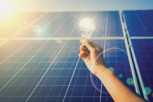 Man holding light bulb in front of cold storage solar panels